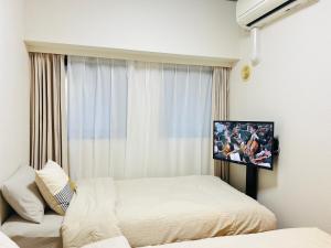 een slaapkamer met 2 bedden en een tv aan de muur bij Jun KBK 306 in Tokyo