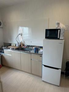 a kitchen with a microwave on top of a refrigerator at 駅1分空港Airport近い in Tokyo