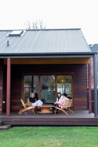 a group of people sitting on the porch of a house at The Wooden House in Bright