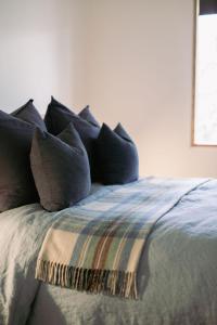 uma cama com almofadas azuis e um cobertor em The Wooden House em Bright