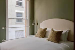 1 dormitorio con cama blanca y ventana en Native Kings Wardrobe, en Londres