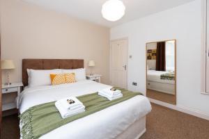 a bedroom with a large white bed with towels on it at Beautiful 2BR Flat, Peaceful Dulwich, South London in London