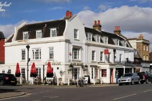 a white building with red umbrellas on a street at Beautiful 2BR Flat, Peaceful Dulwich, South London in London