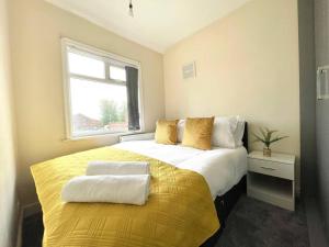 a bedroom with a yellow and white bed with a window at (S12) Bright 3 Bed Home With Free Parking Leeds in Killingbeck