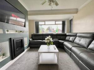 uma sala de estar com um sofá de couro e uma mesa em (S12) Bright 3 Bed Home With Free Parking Leeds em Killingbeck