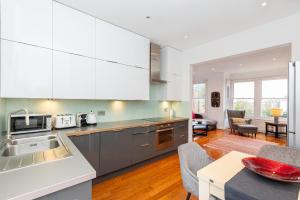 eine Küche mit weißen Schränken und ein Wohnzimmer in der Unterkunft Beautiful 2BR Flat, Peaceful Dulwich, South London in London