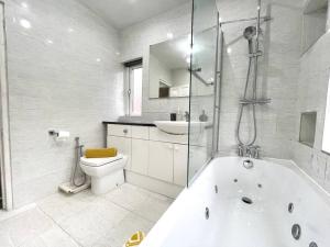 a white bathroom with a tub and a toilet at (S12) Bright 3 Bed Home With Free Parking Leeds in Killingbeck