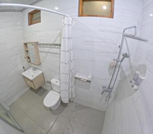 a white bathroom with a toilet and a sink at Omah Nogotirto Homestay Jogja in Ngingas