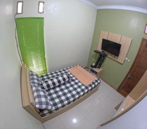 Habitación pequeña con cama y TV. en Omah Nogotirto Homestay Jogja, en Ngingas