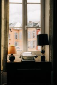 a desk with a lamp and a keyboard and a window at La Maison de Laulie in Bagnères-de-Bigorre