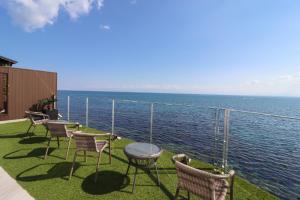 een groep stoelen en tafels op een balkon met uitzicht op het water bij La se ri Resort and Stay in Himi