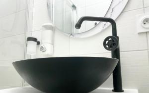 ein Bad mit einem schwarzen Waschbecken und einem Spiegel in der Unterkunft Arina & Julien La Défense-Paris in Suresnes