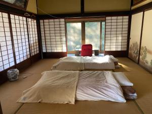 Pokój z 3 łóżkami z białą pościelą i oknami w obiekcie Private stay 120years old Japanese-style house w Okinoshimie