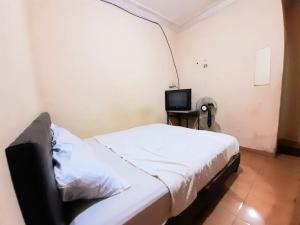 Dormitorio pequeño con cama y TV en SPOT ON 93326 Pondok Anie Syariah, en Pekanbaru