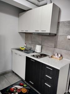 a kitchen with white cabinets and apples on the floor at Studio 10 in Mamaia Sat/Năvodari