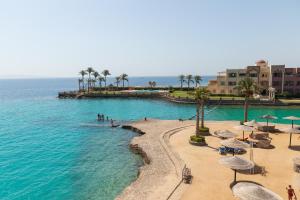 a swimming pool with umbrellas and the ocean at Sunny Days Mirette Family Resort in Hurghada