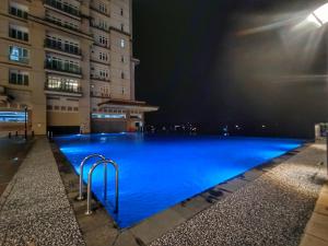 een groot blauw zwembad 's nachts met gebouwen bij Let's Go Homestay in Kuching