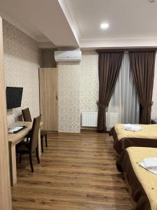 una camera d'albergo con 2 letti, un tavolo e una scrivania di Apart Hotel Vera a Tbilisi City