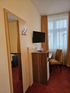 een hotelkamer met een televisie en een bureau met een spiegel bij Hotel U Divadla in Znojmo