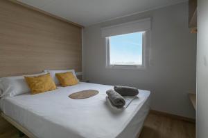 1 dormitorio con 1 cama blanca grande y ventana en Camping tres estrellas Mediterráneo en Xilxes