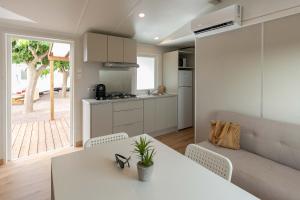 cocina y sala de estar con mesa blanca y sillas en Camping tres estrellas Mediterráneo en Xilxes
