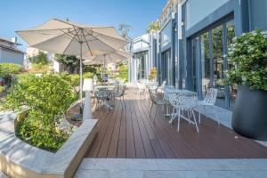 a patio with tables and chairs and an umbrella at H&ocirc;tel Mil&eacute;ade L'Orangeraie - Menton in Menton