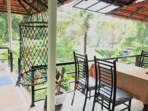 a dining room with a table and chairs and a window at Marari Charlys Homestay in Mararikulam