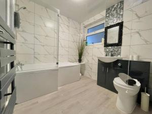 a bathroom with a toilet and a tub and a sink at (S13) Spacious, Bright, Private Family Home in Roundhay