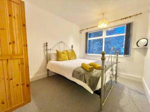 a bedroom with a bed with yellow pillows and a window at (S13) Spacious, Bright, Private Family Home in Roundhay