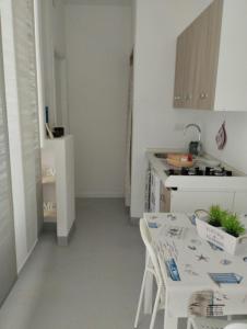 a white kitchen with a table and a sink at Casa Alma monolocale per 2 persone in Porto Ercole
