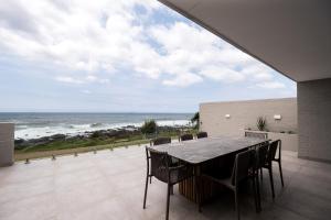 a patio with a table and chairs and the ocean at The Blonde Bungalow Ballito in Ballito