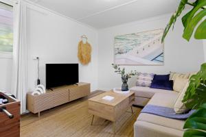 a living room with a couch and a flat screen tv at Bonus Studio Space in Budgewoi