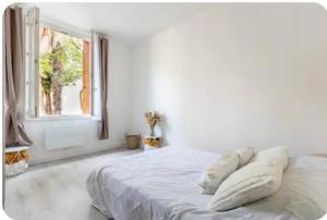 een witte slaapkamer met een bed met kussens en een raam bij Maison cosy Paris Orly jardin privée in Vitry-sur-Seine