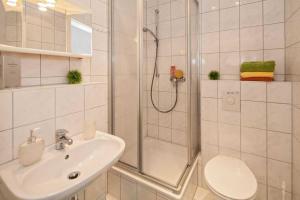 een badkamer met een douche, een wastafel en een toilet bij Pension Haus Antje in Ahlbeck