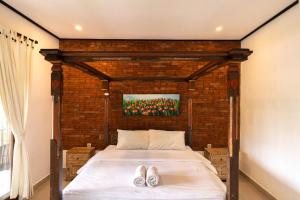 a bedroom with a bed with two shoes on it at Bramasa Ubud Guest House in Ubud