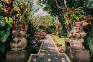 un chemin dans un jardin avec des statues en pierre dans l'établissement Bramasa Ubud Guest House, à Ubud