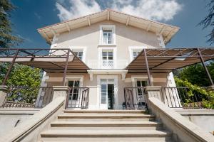 uma grande casa branca com escadas em frente em Maison Martouret - Colodge em Andrézieux-Bouthéon