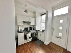 a kitchen with white cabinets and a washer and dryer at (S17) Convenient 2BR Leeds - Sleeps 4 in Leeds