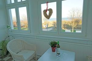 ein weißes Zimmer mit einem Tisch, einem Stuhl und 2 Fenstern in der Unterkunft Villa Emanuel mit Meerblick in Ahlbeck