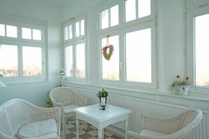 Cette chambre comprend des chaises blanches, une table et des fenêtres. dans l'établissement Villa Emanuel mit Meerblick, à Ahlbeck