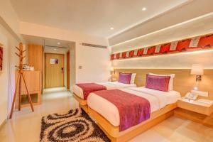 a hotel room with two beds with purple pillows at The SSK Solitaire Hotel & Banquets in Nashik