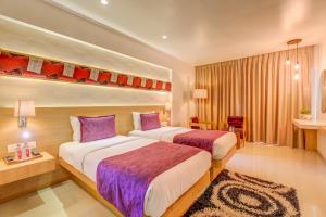 two beds in a hotel room with purple pillows at The SSK Solitaire Hotel & Banquets in Nashik