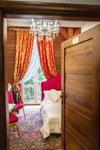 1 dormitorio con cama y lámpara de araña en Łódzki Pałacyk - Pokoje pałacowe, en Łódź