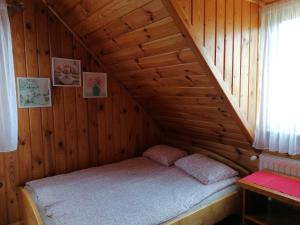 małe łóżko w drewnianym domku z oknem w obiekcie Noclegi Gaja w miejscowości Święta Katarzyna