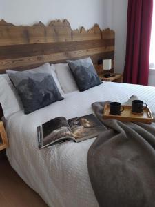 Una cama con una bandeja con dos tazas y un libro en Casa Salvaterra Suite 44, en Pinzolo