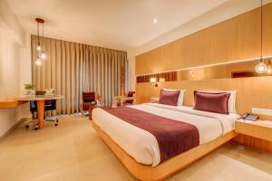 una camera d'albergo con un grande letto e una scrivania di The SSK Solitaire Hotel & Banquets a Nashik