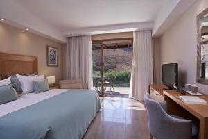 a bedroom with a bed and a desk and a television at Atlantica Aegean Park in Kolymbia