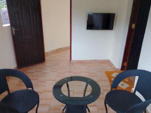 Zimmer mit 2 Stühlen, einem Tisch und einem TV in der Unterkunft Blessing holiday homes - Diani Beach in Diani Beach