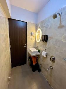 a bathroom with a sink and a mirror and a door at La Alba 1 BHK Serviced Apartment in Mumbai