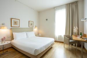 una camera d'albergo con un grande letto bianco e una scrivania di Cosmo Hotel Palace a Cinisello Balsamo